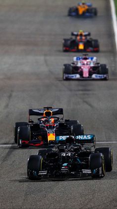 three racing cars driving on a track with one behind the other in front of them