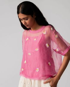 The Gulbahar Pink Organza Top by Serai is a beautifully ethereal piece made from sheer organza silk fabric. Its delicate, lightweight texture is complemented by a cotton/silk slip underneath, providing coverage while maintaining the top's translucent charm. The top features a minimalist floral design, enhancing its elegant and airy appearance. Organza Tops With Sheer Sleeves, Feminine Organza Tops For Spring, Sheer Organza Tops For Wedding, Sheer Organza Wedding Tops, Organza Blouse With Chikankari Embroidery, Sheer Silk Tops, Sheer Organza Tops For Spring, Fitted Organza Blouse For Summer, Feminine Silk Chiffon Blouse For Spring