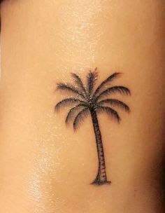 a small palm tree tattoo on the back of a woman's stomach is shown