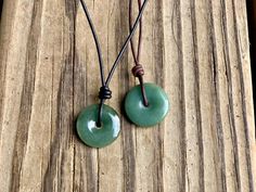 A donut shaped, shiny green jade pendant is hand knotted on leather cord for a bit of a good luck charm. Jade is known as the lucky gemstone and is also considered a stone of wealth. A sliding knot closure lets you wear the necklace long or short depending on your mood! Pendant is slightly smaller than a quarter. Jade comes in variety of shades of green. Your piece may vary from those pictured. At its longest, the necklace is about 27" in length, not including the pendant. Leather jewelry should Donut Gemstone Necklaces, Adjustable Green Necklace With Waxed Cord, Adjustable Green Waxed Cord Necklace, Green Waxed Cord Jewelry With Sliding Knot, Adjustable Jade Necklace For Good Luck, Adjustable Round Aventurine Necklace, Green Waxed Cord Necklace For Gifts, Sliding Knot Closure, Donut Shape