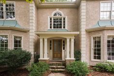 the front entrance of a house with steps leading up to it and bushes growing on both sides