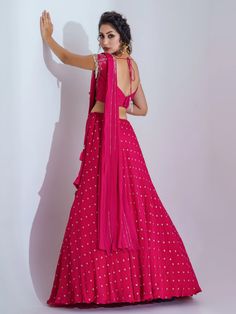 A three-piece dark pink lehenga set from the Suruchi Parakh collection. This beautiful dark pink lehenga is paired with a hand-embroidered blouse. The dark pink color with sequin work enhances the graceful georgette crepe lehenga. The lehenga has side hanging heart tassels to the waistline. And the blouse has a tassel tie-up at the back. The hand-embroidered blouse has intricate floral embroidery work along with tassels at the sleeve hemline. The outfit is completed with a pre-drape dupatta atta Unstitched Pink Choli For Party, Pink Lehenga With Traditional Drape, Pink Georgette Choli With Traditional Drape, Traditional Drape Pink Lehenga With Motifs, Pink Floor-length Pre-draped Saree With Dori Work, Pink Floor-length Pre-draped Saree For Festive Occasions, Pink Floor-length Pre-draped Saree For Eid, Pink Anarkali Style Pre-draped Floor-length Saree, Anarkali Style Pink Floor-length Pre-draped Saree