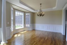 an empty room with hard wood floors and chandelier