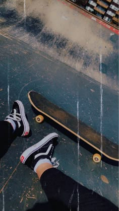 a person standing next to a skateboard on top of a floor in the rain