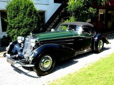 an old black car parked in front of a house