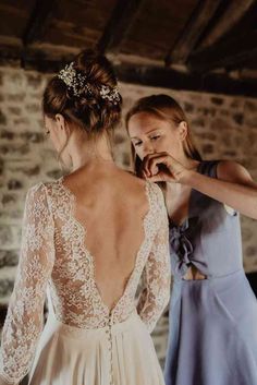 two women in dresses standing next to each other and one is fixing the back of another woman's dress