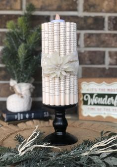 Bringing LIFE to old books - Book page candle.  Our pillar candle book art is adorned with a quality ribbon, flower accent and a tealight.  9" tall and 4" wide *Follow us on Facebook and Instagram to see all of our creations. Grace, Love and Happiness! Christmas Book Art, Pillar Candle Wedding, Vintage Book Centerpiece, Book Art Christmas, Music Centerpieces, Cereal Box Craft, Pillar Candles Wedding, Book Centerpieces, Book Themed Wedding