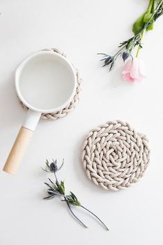 a white table topped with flowers and a magnifying glass next to a rope coaster