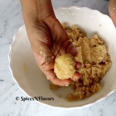 a person is picking up food from a white bowl on a marble counter top with their hands