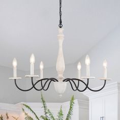 a chandelier hanging from the ceiling in a kitchen with potted plants on the counter