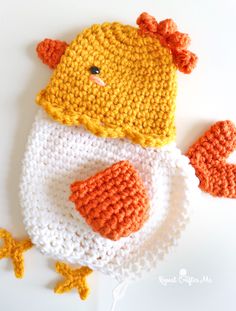 a crocheted chicken hat and mitten set on a white surface with an orange duck