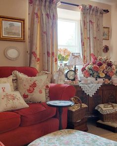 a living room filled with furniture and flowers on the window sill next to a table