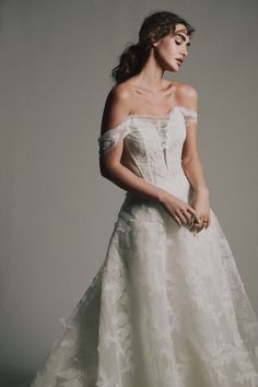 a woman in a white wedding dress posing for the camera with her hand on her hip