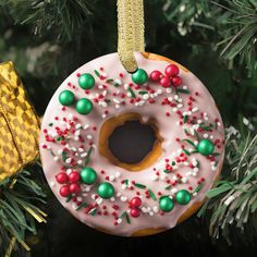 a donut ornament hanging from a christmas tree with candy sprinkles