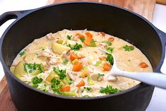 a pot filled with soup on top of a wooden cutting board