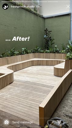 a wooden bench sitting on top of a wooden floor next to a green wall and planters