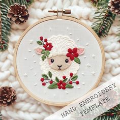 an embroidered sheep with holly and berries on it's face is surrounded by pine cones