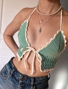 a woman wearing a green crochet top and jeans