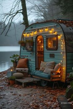 an old camper is decorated with fairy lights and pillows for the front porch area