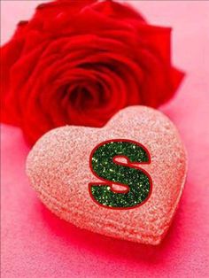 a heart shaped box with the letter s on it next to a rose