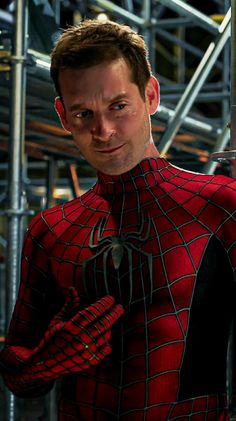 a man in a spider - man suit standing next to a metal scaffolding