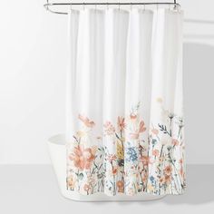 a shower curtain with flowers on it and a white tub in front of the window