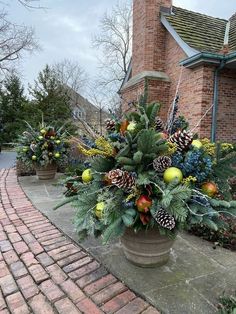 a potted plant with pine cones and other christmas decorations on the side of a brick building