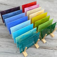 there are many different colored glass pieces on the stand together, each with a wooden base