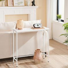 a white couch sitting next to a table with a clock on it's side