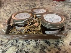 four jars of jam sitting on top of a counter next to a glass container filled with dried herbs