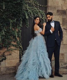 a man in a tuxedo standing next to a woman in a blue dress