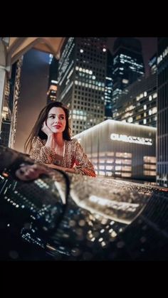 a woman sitting on top of a car in the city