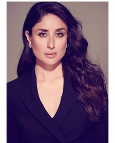 a woman with long dark hair wearing a black blazer and earrings, posing for the camera