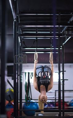 a woman hanging upside down in a crossfit gym with her hands on the bars