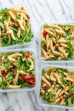 four plastic containers filled with pasta salads on top of a marble countertop,