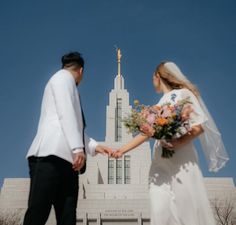 a bride and groom holding hands in front of the mormon temple