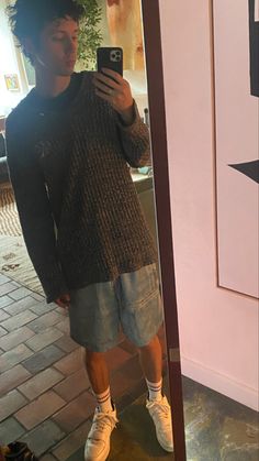 a man standing in front of a mirror taking a selfie with his cell phone