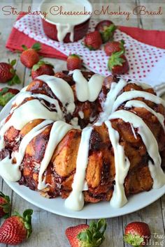 strawberry cheesecake monkey bread with icing on a white plate next to strawberries