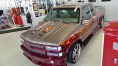 a silver truck with flames painted on it's hood parked in a showroom