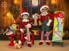 two elfs are standing in front of a candy bar and an assortment of toys