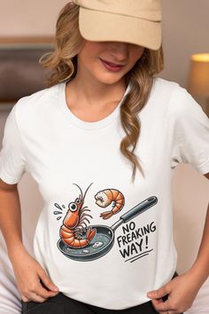 Get ready to turn heads with this hilarious unisex T-shirt featuring a surprised cartoon shrimp in a frying pan with the text "No Freaking Way." Perfect for seafood lovers and cooking enthusiasts, this tee adds a playful touch to your wardrobe. Made from high-quality, comfortable fabric, it's ideal for casual outings, seafood parties, or just lounging at home. Whether you're a fan of shrimp, enjoy funny graphics, or want to gift someone with a unique and humorous shirt, this tee is a must-have. Available in various sizes for both men and women. We utilize the authentic Bella Canvas 3001 brand, renowned for its UNISEX design, making it one of the most sought-after shirts in the market. Prior to placing an order, kindly refer to our size chart. It can be located in both the listing's images Funny Crew Neck T-shirt With Front Print, Cartoon Shrimp, Shrimp Cooking, Cooking Shirt, Seafood Party, How To Cook Shrimp, Funny Graphics, Frying Pan, Frying