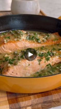 a pan filled with fish and vegetables on top of a wooden cutting board