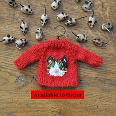 there is a red sweater with a cat on it next to other small animal heads