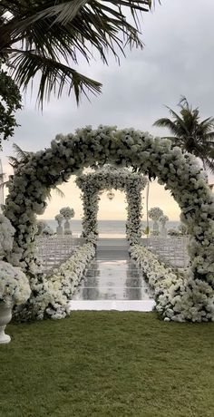 an outdoor wedding setup with white flowers and greenery on the grass, surrounded by palm trees