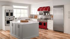 a kitchen with white cabinets and stainless steel appliances, including an island in the middle