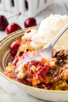 a close up of a bowl of food with ice cream and cherries on the side