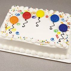 a birthday cake decorated with balloons and confetti on a white plate sitting on a table