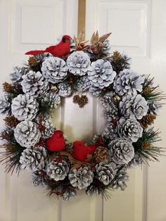 a wreath with pine cones and two red birds