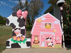 two cardboard farm animals and a pink barn with a cow on the front yard, one has a pink bow around it's neck