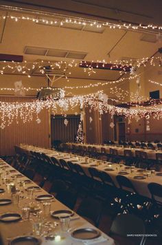 tables and chairs are set up for an event with lights strung from the ceiling above them